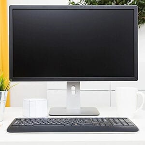 A computer monitor and keyboard on top of a desk.