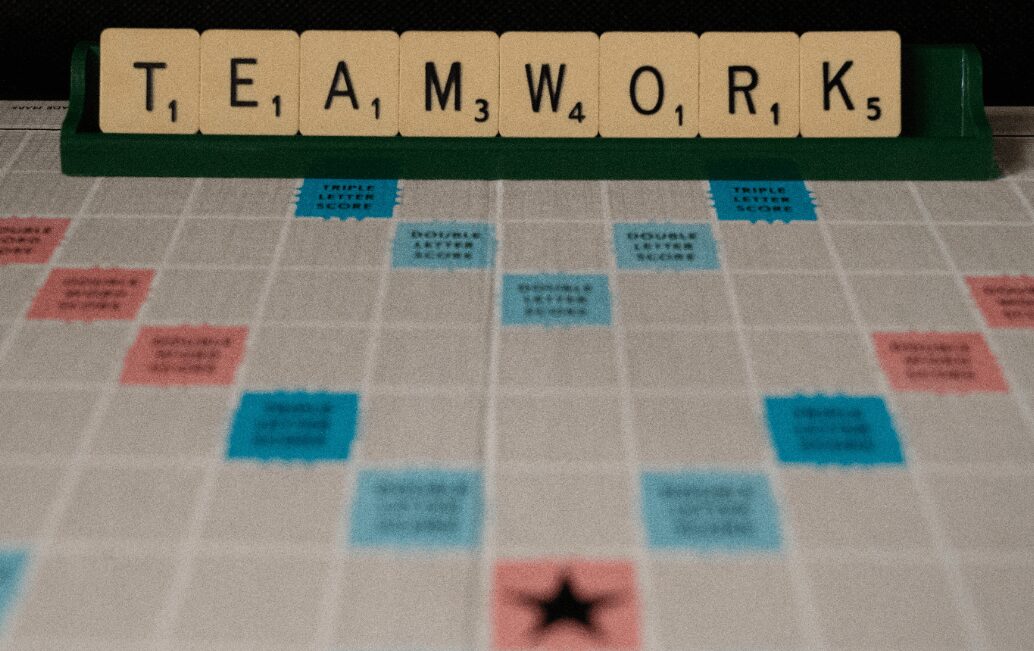 A scrabble board with the word teamwork spelled out in letters.